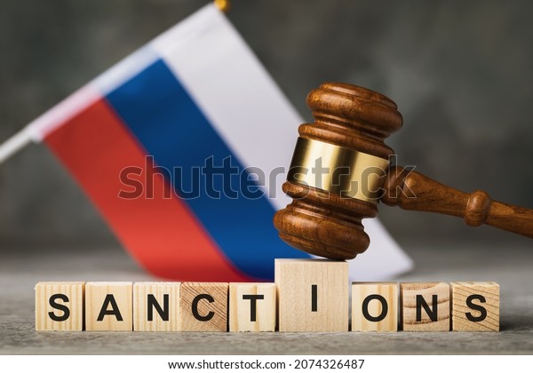 judge\'s gavel, wooden cubes with the text on the\
background of the Russian flag, the concept on the topic of\
sanctions in Russia