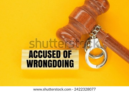judge's hammer, iron handcuffs and sticks with the words accused of wrongdoing. the concept of accusation of wrongdoing.