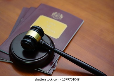 A Judge's Hammer With The Local Law Book Of Malaysia With Public Government Logo.