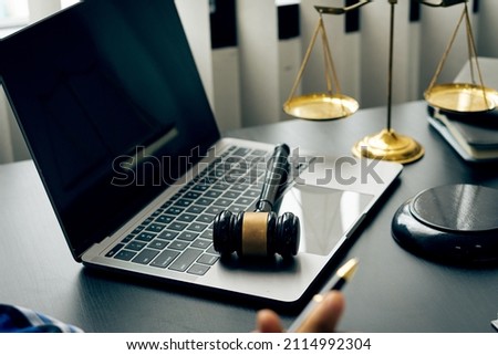 A judge's hammer is placed on a laptop with a scale next to the lawyer's adviser idea.