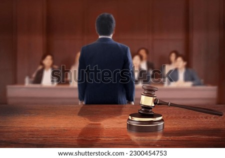Judge's hammer symbolizes the judgment on the judicial wooden table in courtroom front of the lawyer talk to jury on courtroom on background