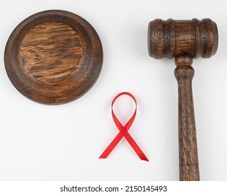 Judicial Gavel And Red Ribbon On A White Background. Symbol Of The Fight Against AIDS.