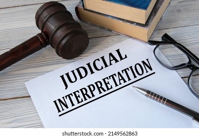 JUDICIAL INTERPRETATION - Words On White Paper With The Background Of The Judge's Hammer, Glasses And Pen