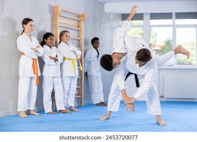 Judo coach shows fighting techniques in sparring with a boy for a group of young athletes - Powered by Shutterstock