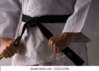 judo fighter poses in white kimono with black belt. Japanese judo and 
jiu jitsu