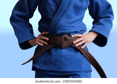 Judo girl with brown belt. A judoka teenager fighter poses in a blue kimono on a plain background. Japanese martial art. The process of martial arts training. Healthy lifestyle, sports concept - Powered by Shutterstock