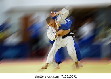 Judoka in white judogi attempting to throw opponent in blue judogi with Sode Tsurikomi Goshi - Powered by Shutterstock