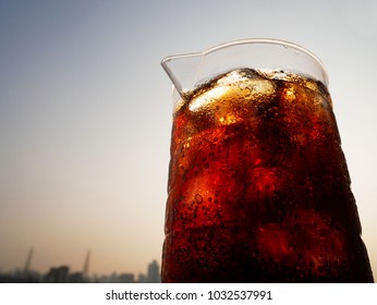 Jug Of Cola Softdrink With Bright Sky, City