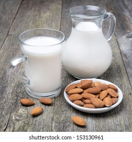 Jug And Glass Cup With Almond Milk On The Wooden Table