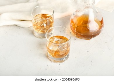 Jug And Glasses Of Cold Whiskey On Light Background