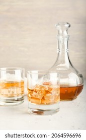 Jug And Glasses Of Cold Whiskey On Light Background