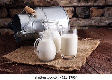 A jug of milk and glass of milk on a wooden table - Shutterstock ID 721417984