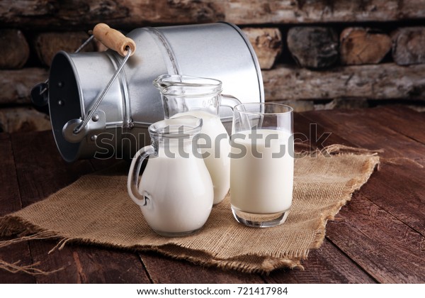 A jug of\
milk and glass of milk on a wooden\
table