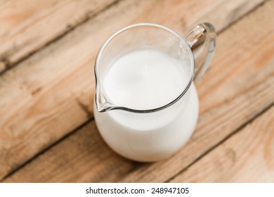 Jug Of Milk On Old Wooden Table. Top View