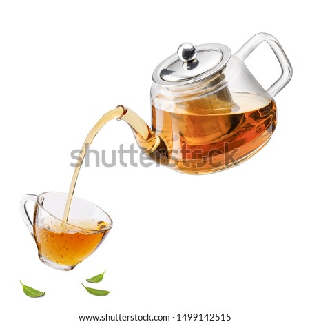 Jug pouring hot tea into glass cup with green tea leaves in the air, Healthy products by organic natural ingredients concept, Empty space in studio shot isolated on white background