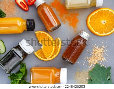 Juice shots for a healthy lifestyle, flat lay on dark grey with ingredients