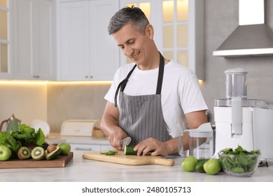 Juicer and fresh products on white marble table. Smiling man cutting cucumber in kitchen - Powered by Shutterstock