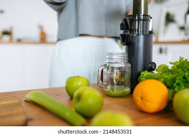 The Juicer Stands On A Wooden Table And Pours Celery Juice Into A Glass Close Up