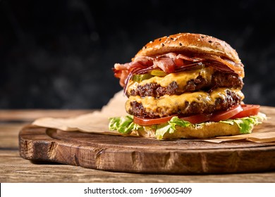 Juicy American burger, hamburger or cheeseburger with two beef patties, with sauce and basked on a black background. Concept of American fast food. Copy space - Shutterstock ID 1690605409