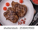 Juicy beef steak grilled with salt, spices and herbs on a dark textured background