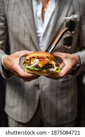 Juicy burger held by man in a vintage suit.  - Shutterstock ID 1875084721