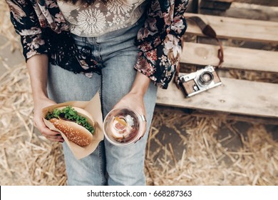 juicy burger and lemonade in hands, top view. stylish hipster woman holding cheeseburger and refreshing drink. boho girl at street food festival. summer vacation picnic. space for text