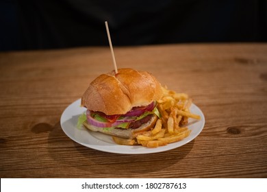 Juicy Burger On A White Plate With Fries