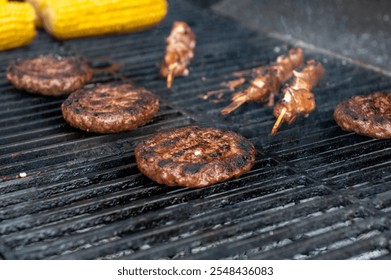 Juicy burgers and meat skewers cooking on a grill alongside golden corn cobs, capturing the essence of outdoor cooking - Powered by Shutterstock