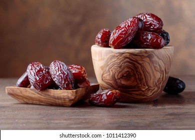 Juicy dates in a bowl on a old wooden table .
