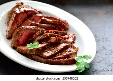 Juicy Flank Steak In An Oval White Plate Decorated With Cilantro Leaves 