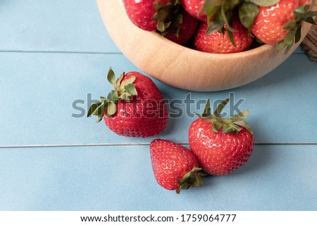 Juicy and fresh organic strawberries in a bowl and some part on a blue wood background.aConcept for healthy nutrition.Close up view.Copy space.