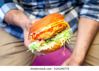 Juicy Fried Chicken Street Burger Holding In One Hand Closeup With Person In The Background