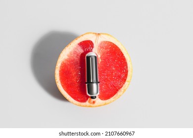 Juicy grapefruit and vibrating bullet from sex shop on light background