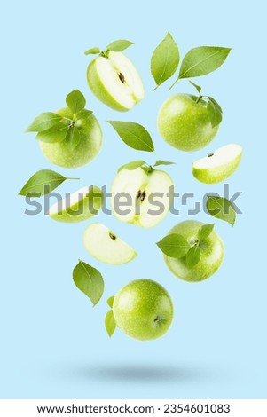 Juicy green apples with green leaves fly or fall on light blue background as art composition, with whole, half, quarter fruit, isolated, shadow. Summer fruits for advertising, design, label product.