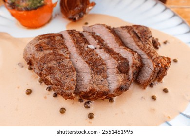 Juicy grilled steak served with pepper sauce and garnished with roasted vegetables at a rustic dining setting - Powered by Shutterstock