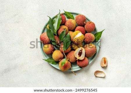 Juicy lychee fruit with cut in half and green leaves, top view. Fresh ripe tropical fruit.
