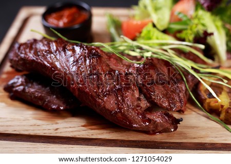 juicy medium rare skirt steak, hanging tender steak served with vegetable salad and potatoes on board, traditional american cuisine,grill and barbeque, meat restaurant menu