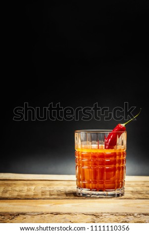 juicy red drink bloody mary with chilli pepper on a wooden table