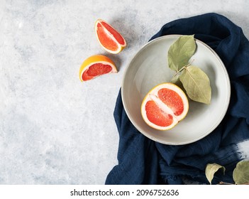 Juicy Red Grapefruit In A Plate And Slices On A Blue Background With A Dark Napkin. Concept Healthy Food. Top View And Copy Space.