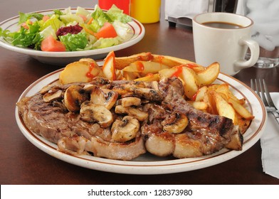 A juicy rib steak with potato wedges and a garden salad - Powered by Shutterstock