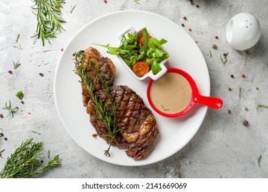 Juicy Ribeye Steak With Pepper Sauce On White Plate Top View