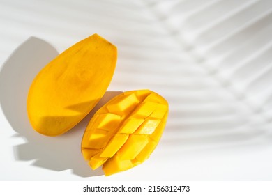 Juicy ripe yellow Thai mango on a white background. Hard light and shadow from a palm tree. Whole and diced mango. - Shutterstock ID 2156312473