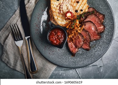 Juicy Roast Beef With Ciabatta In Tomato Sauce Is Beautifully Sliced And Laid Out On Plates. Top View, Beautiful Table Setting, Beautiful Serving, Traditional Italian Food, Gray Background, Copy Space