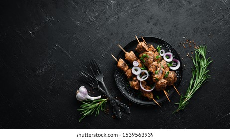 Juicy skewers of meat in a black plate. Barbecue, kebab. Top view. Free copy space.