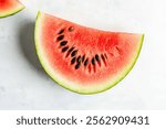 A juicy slice of watermelon, showcasing its bright red flesh, black seeds, and green rind. The vibrant colors and refreshing nature of watermelon are beautifully captured in this image