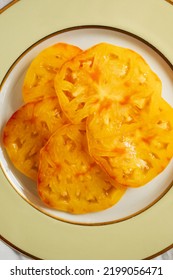 Juicy Sliced Yellow Heirloom Tomato On Pale Yellow, Gold, White Plate