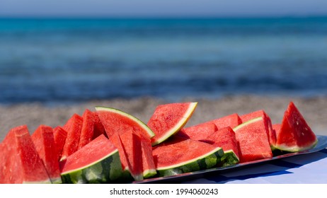 Juicy Slices Of Watermelon On Plate. In The Background The Sea And The Beach. Red Watermelon, Fresh Fruit. Summer Time 