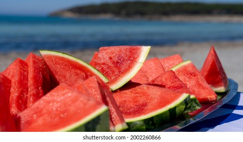 Juicy Slices Of Watermelon On Plate. In The Background The Sea And The Beach. Red Watermelon, Fresh Fruit. Summer Time 