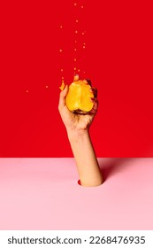 Juicy sweet persimmon. Authentic female hand squeezes half of fruit over pink red background.Pop art food photography. Drops of juice fly up. Concept of healthy eating, art, fashion, ad