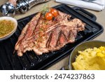 Juicy T-bone steak with grill marks, served with creamy mashed potatoes and a vibrant bowl of chimichurri. Perfect for menus, food blogs, or restaurant ads, showcasing gourmet dining at its finest.